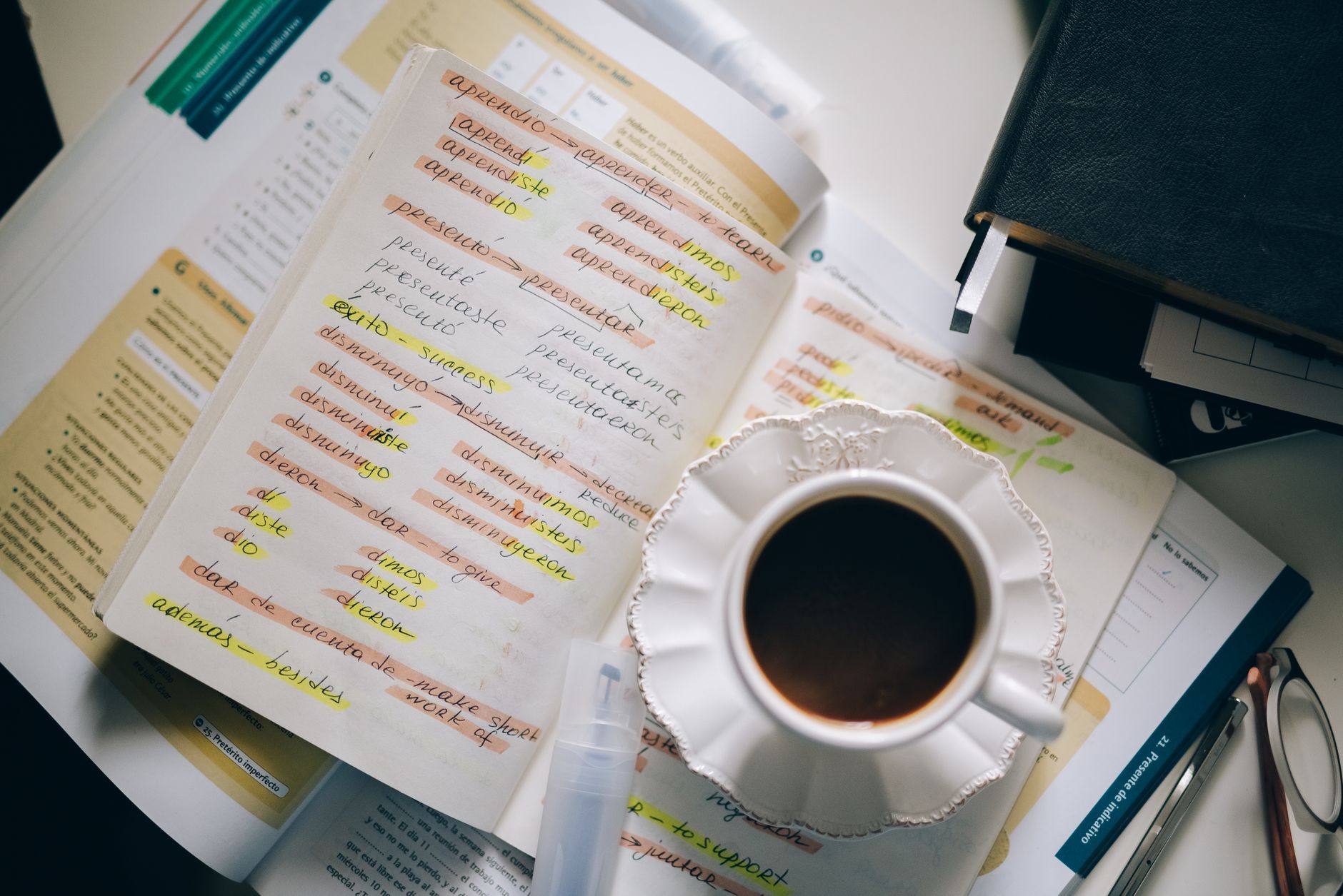 A cup of coffee resting on handwritten language-learning notes